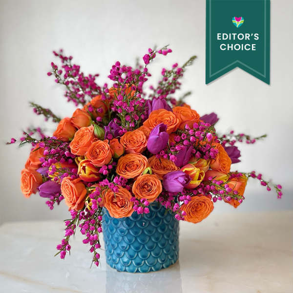 Orange and purple flower arrangement in a blue textured vase