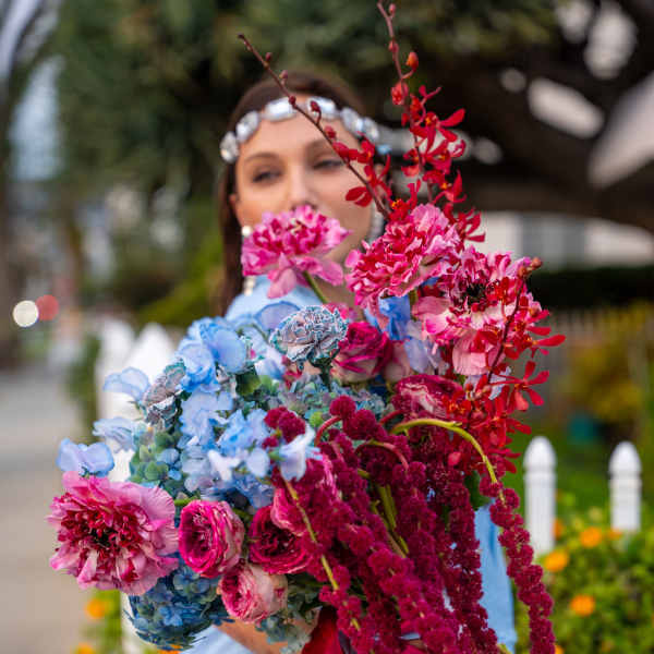 Woman holding a large bouquet of pink, blue, and red flowers