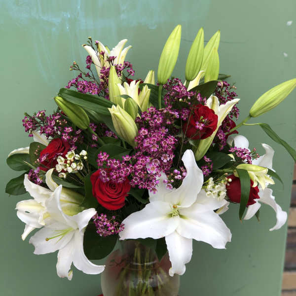Bouquet of white lilies and red roses in a glass vase
