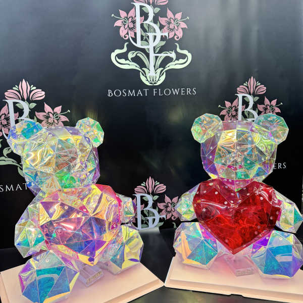 Two iridescent teddy bear sculptures with heart accents on white bases