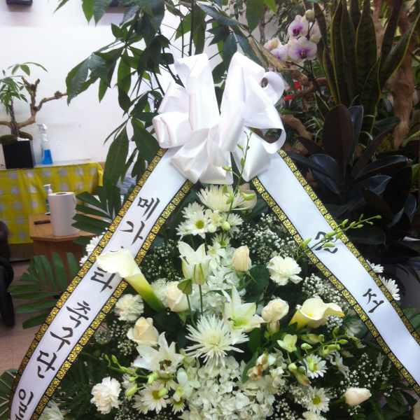 White funeral standing spray with ribbon and mixed flowers