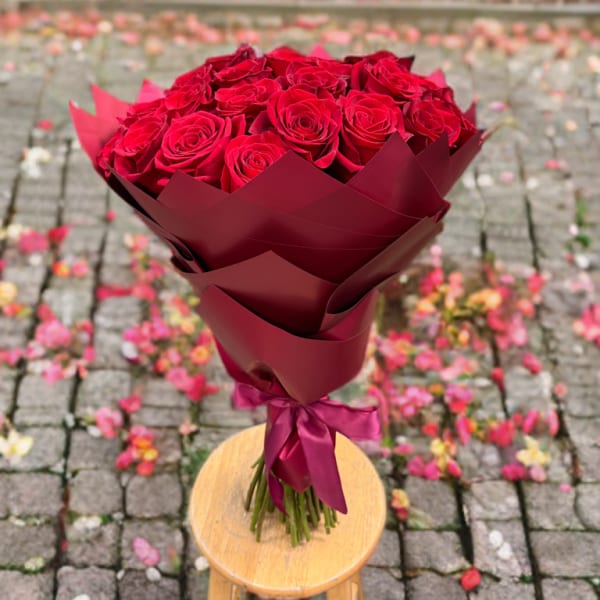 Bouquet of red roses wrapped in burgundy paper with a ribbon