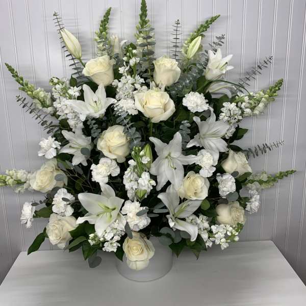 White lilies and roses arranged in a white vase