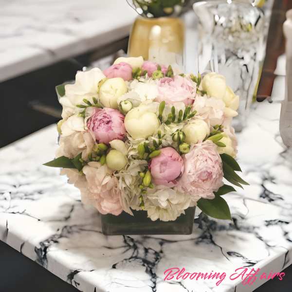 Pink and white bouquet of peonies and hydrangeas in a square vase