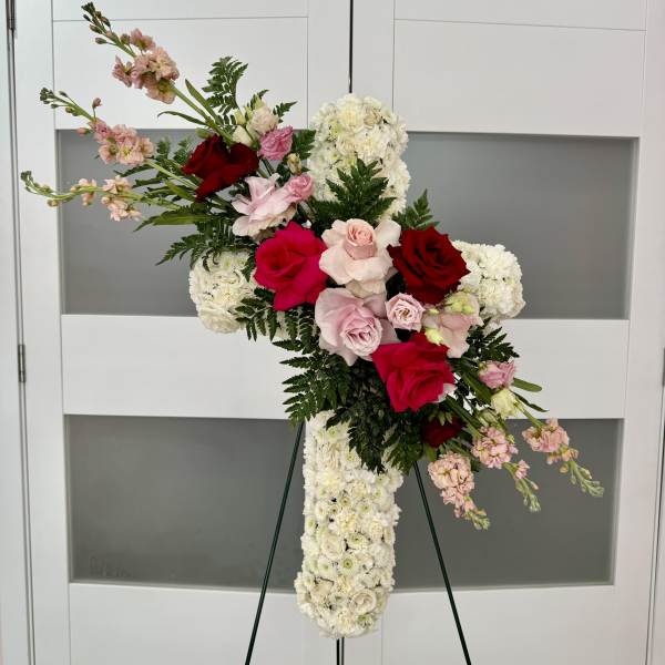 Standing floral spray with red and pink roses and white blooms on an easel