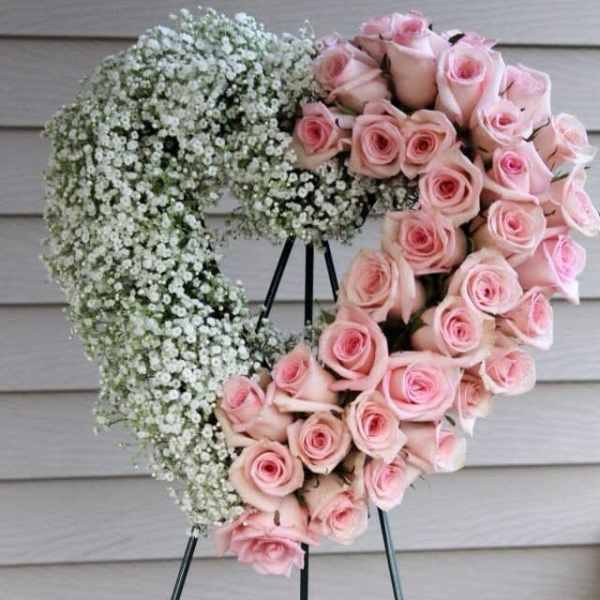 Heart-shaped wreath of pink roses and white baby's breath on a stand