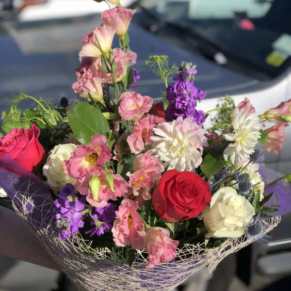 Mixed bouquet of pink, red, white, and purple flowers wrapped in mesh