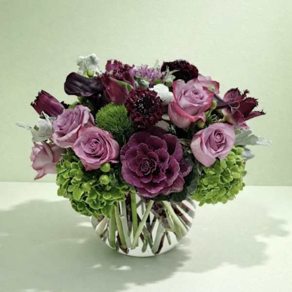Pink and purple rose arrangement in a striped glass vase