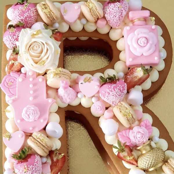 Decorated number-shaped cake with pink candies, strawberries, and a white rose