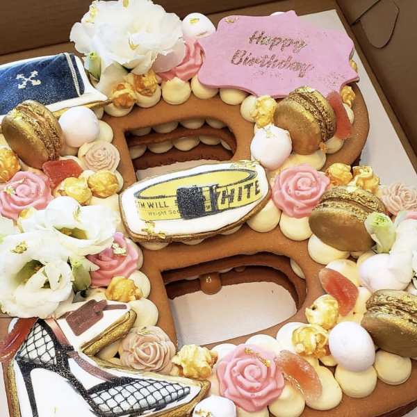 Decorated number-shaped cake with flowers, macarons, and birthday plaques