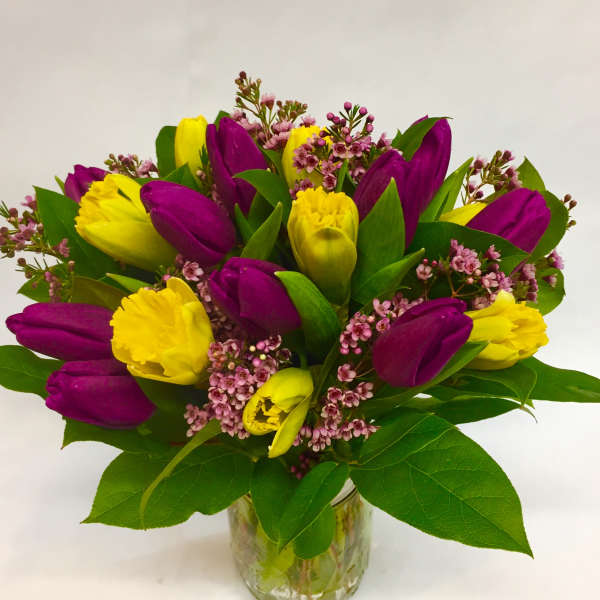 Bouquet of purple and yellow tulips in a glass vase