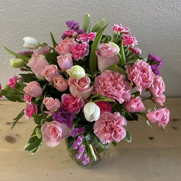 Pink roses and carnations arranged in a glass vase