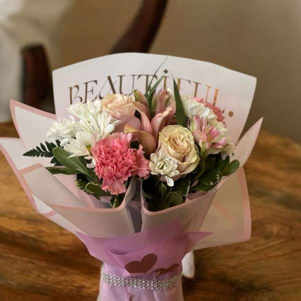 Pink and white bouquet wrapped in decorative paper with a ribbon