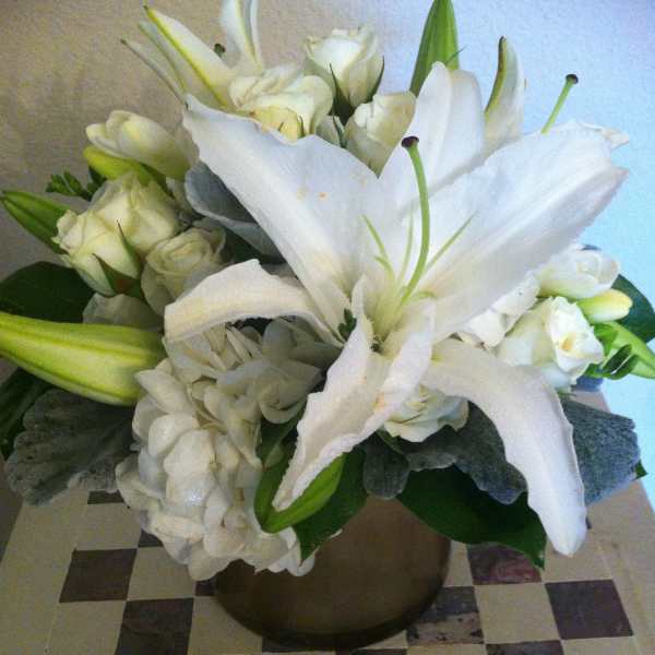 White lilies and roses arranged in a bronze vase