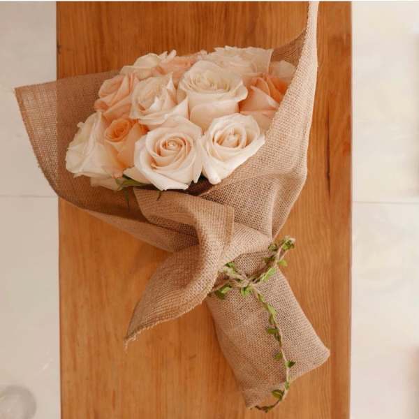 Bouquet of pale peach roses wrapped in burlap