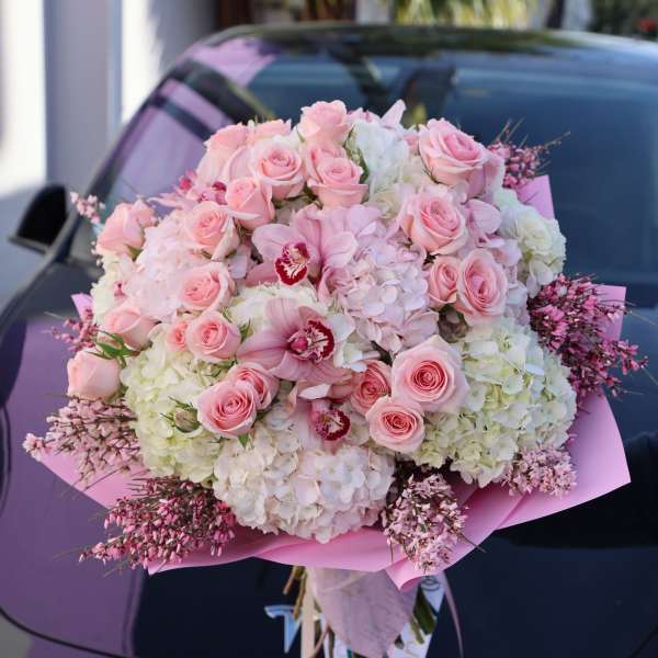 Large pink and white bouquet with roses and orchids wrapped in pink paper