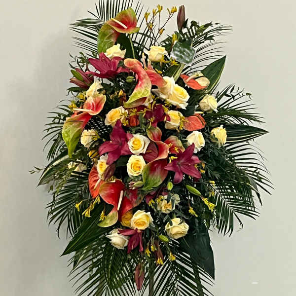 Standing floral spray with roses, anthuriums, and lilies in pink, cream, and red