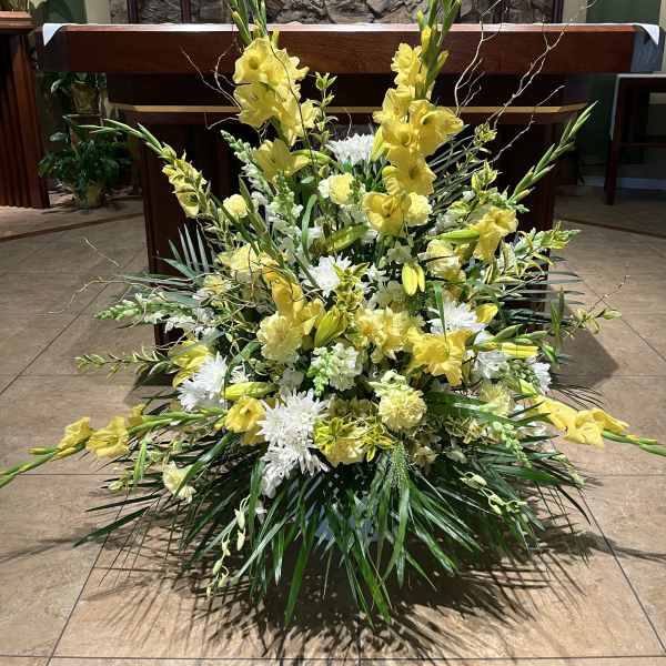 Large yellow and white floral arrangement in front of an altar