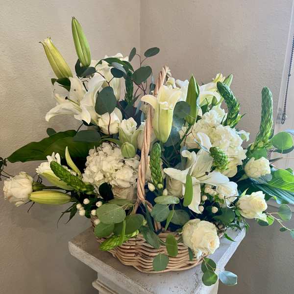 White lilies and roses arranged in a wicker basket