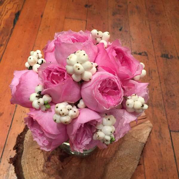 Pink rose bouquet with white berry accents in a small glass vase