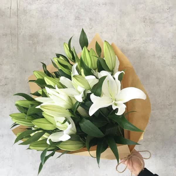 Bouquet of white lilies wrapped in brown paper