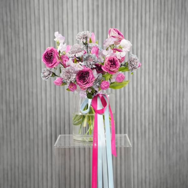 Pink and white bouquet in a glass vase with long ribbon streamers