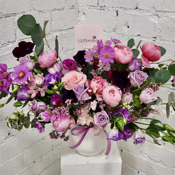 Pink and purple mixed bouquet in a white vase with a ribbon