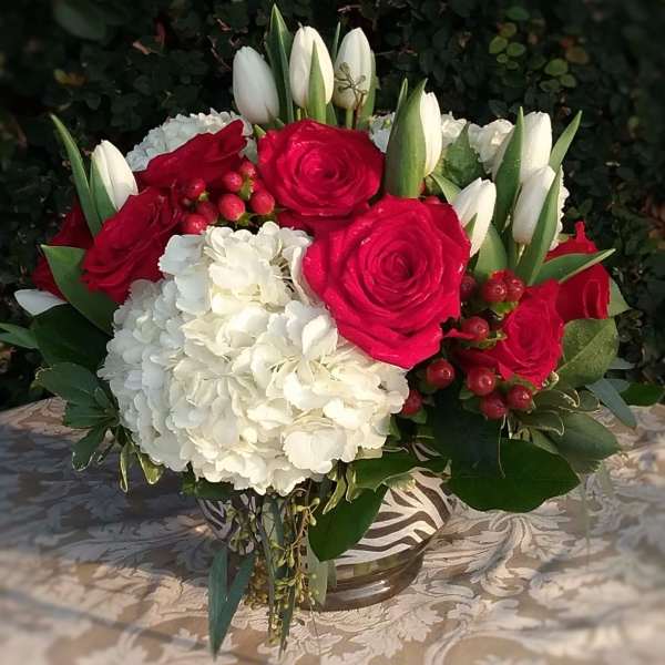Bouquet of red roses, white tulips, and white hydrangea in a glass vase
