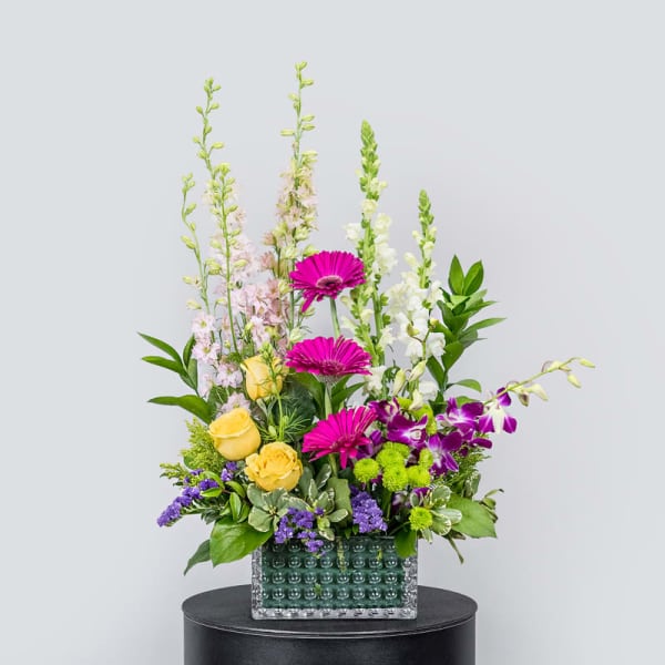 Tall mixed flower arrangement in a textured glass vase