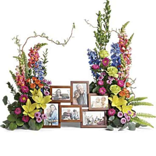 Floral memorial display with framed photos and colorful flowers
