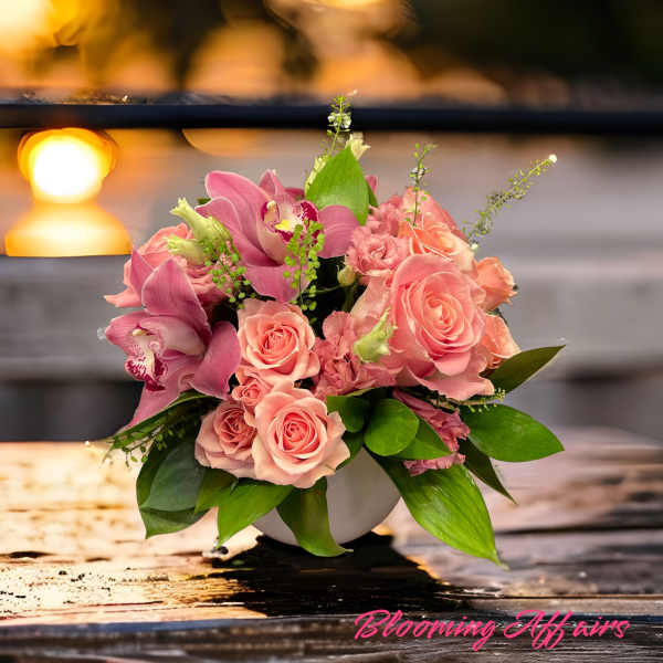 Pink roses and orchids arranged in a white bowl vase