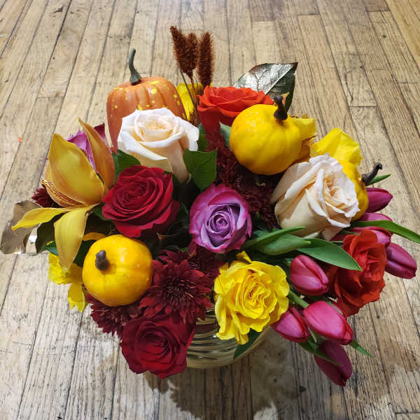 Mixed bouquet with roses, tulips, and small pumpkins in a glass vase