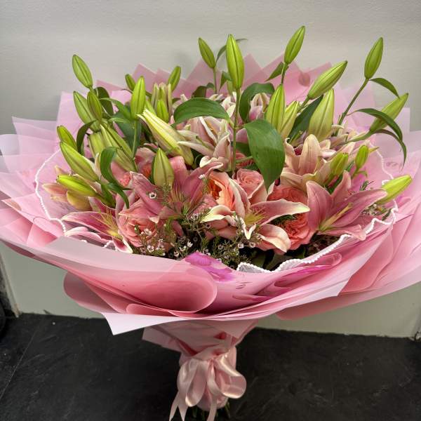 Pink bouquet of lilies and roses wrapped in pink paper