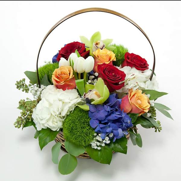 Basket of mixed roses, hydrangeas, and orchids with a metal handle
