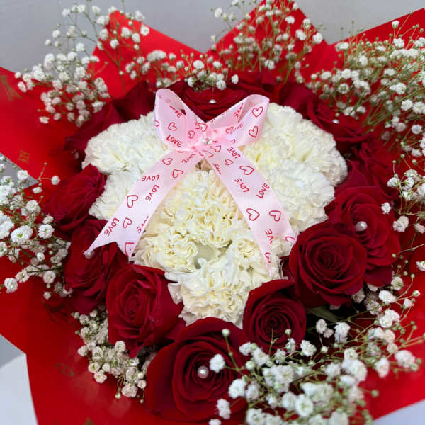 Red roses and white carnations with baby's breath, tied with a pink ribbon