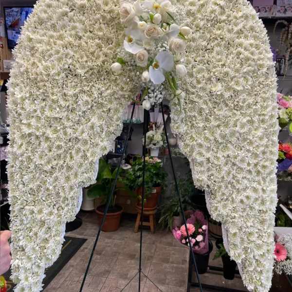 Large white floral funeral spray on a stand with orchids and roses