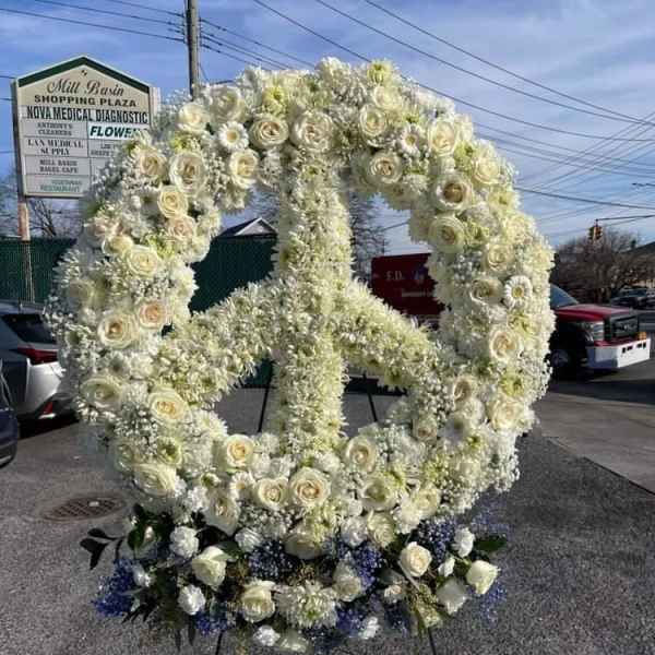 Large white floral peace sign display with blue ribbon bows