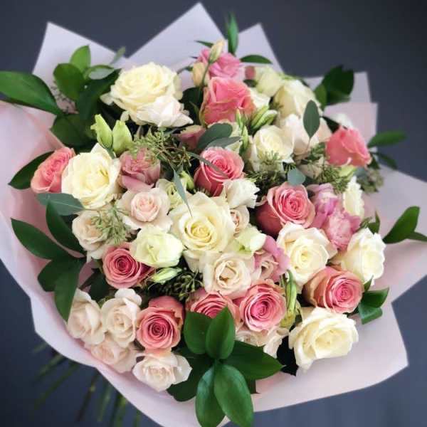 Bouquet of pink and cream roses wrapped in pale paper