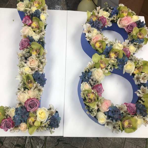Floral arrangement shaped like the number 18 with roses and orchids