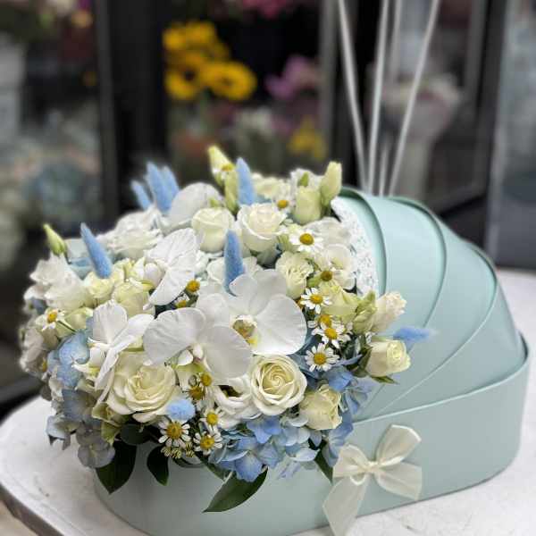 White and pale blue floral arrangement in a mint gift box