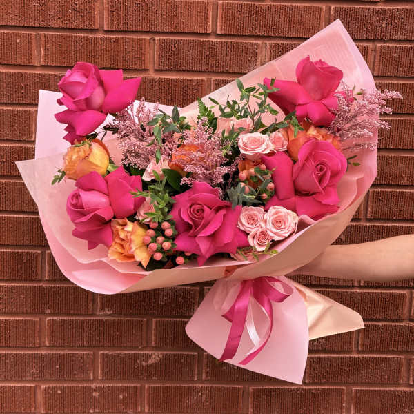Pink rose bouquet wrapped in pale pink paper with a ribbon