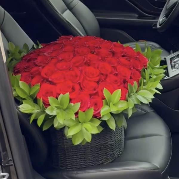 Large bouquet of red roses in a black basket on a car seat