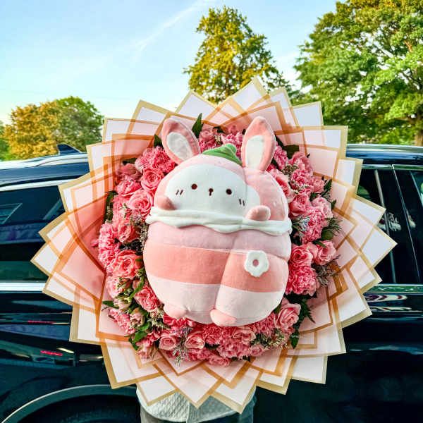 Pink flower bouquet with a plush bunny centerpiece