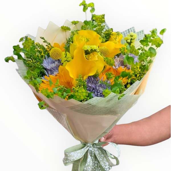 Hand-tied bouquet of yellow and purple flowers wrapped in pale paper