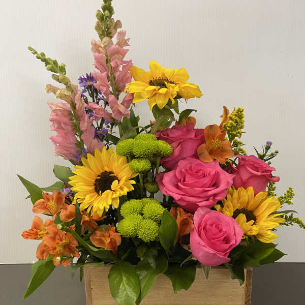 Mixed bouquet with pink roses, sunflowers, and orange alstroemeria in a wooden box
