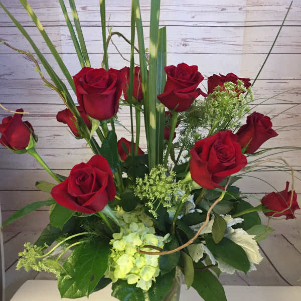 Red roses and pale green hydrangea in a clear glass vase