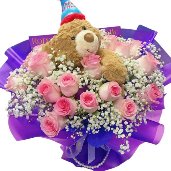 Pink roses arranged with a teddy bear in a birthday hat
