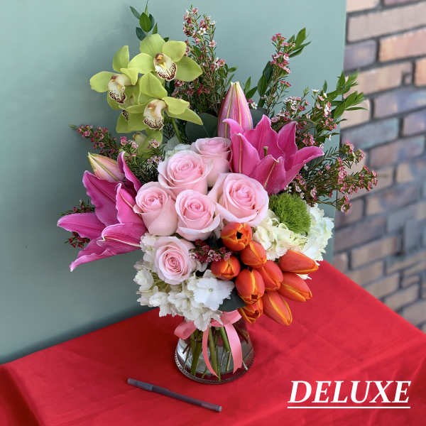 Bouquet of pink roses, lilies, and orchids in a glass vase