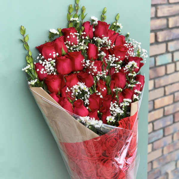 Bouquet of red roses with small white filler flowers in clear wrap