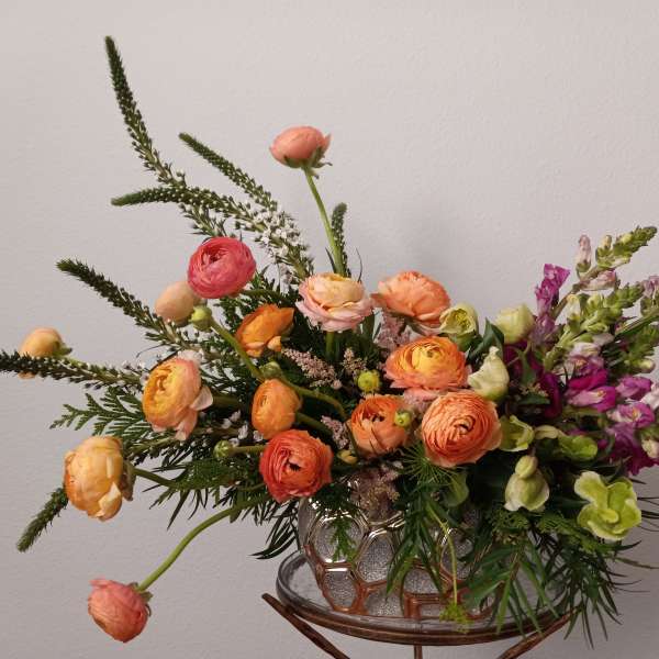 Mixed bouquet of orange and pink flowers in a glass vase